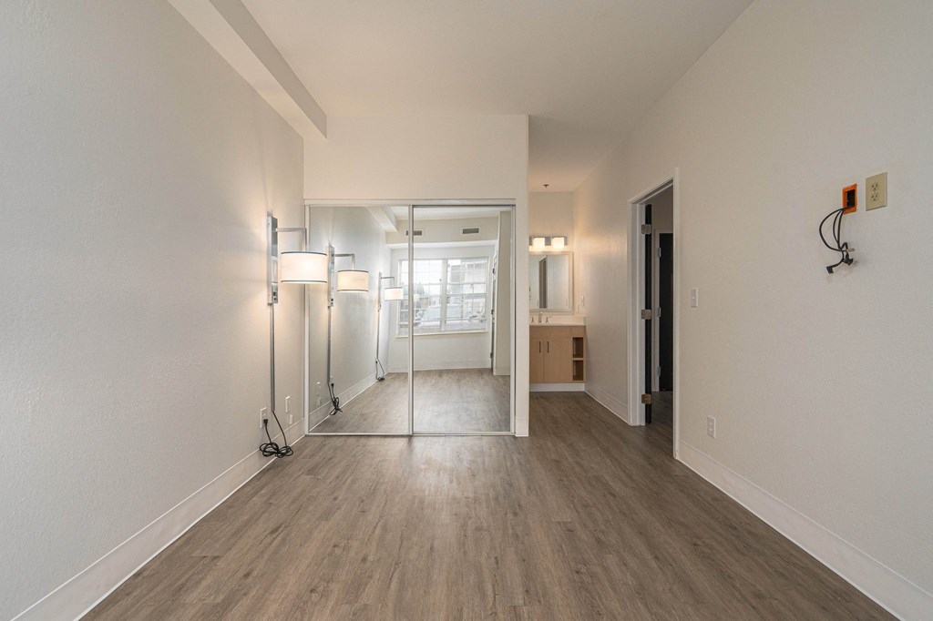 an empty living room with a mirrored closet and a bathroom